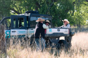 Ranch and Recreation brokers walking a buyer through Outpost Ranch beside a branded #1 Properties side-by-side